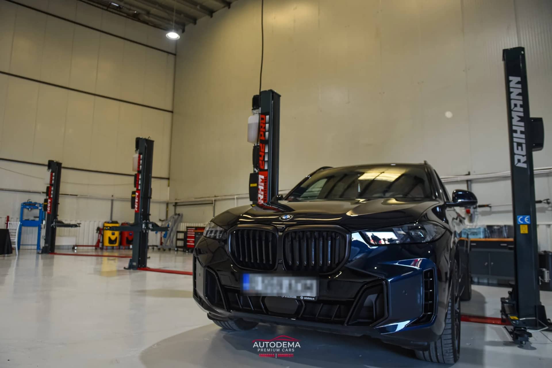 BMW X5 negru parcat în hala din Otopeni, între elevatoare cu două coloane